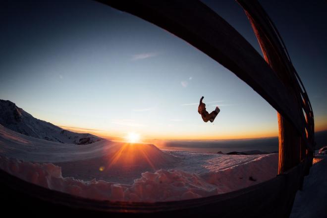 Un snowboarder hace un salto en un atardecer en Sierra Nevada.