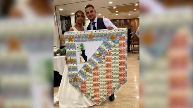 Los novias posando con el escudo del Atleti hecho con billetes de verdad.