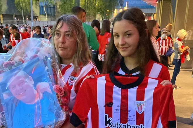 La hermana y la sobrina del fallecido socio tomatero Joseba Larrondo con un ramo y una camiseta firmada por la plantilla del Athletic Club.