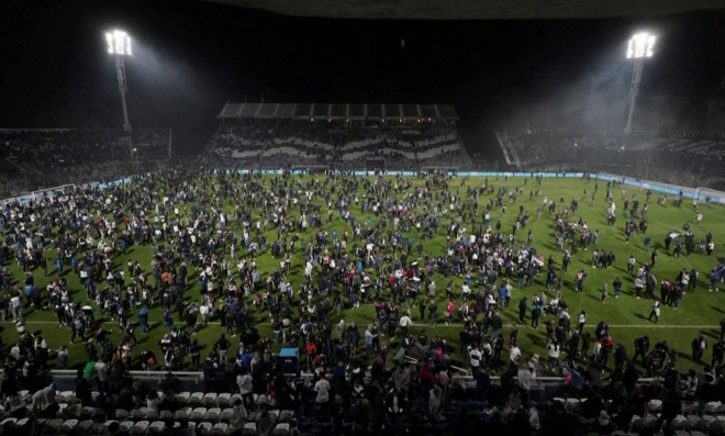 Los aficionados, sobre el terreno de juego para escapar de los gases. (Reuters)