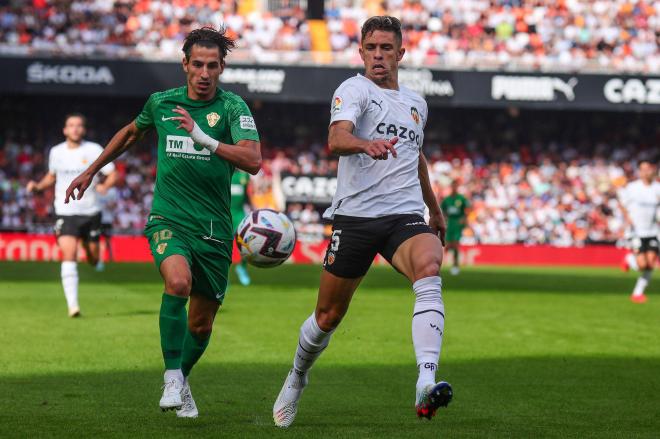 Pere Milla pelea un balón con Paulista en el Valencia-Elche (Foto: Cordon Press).