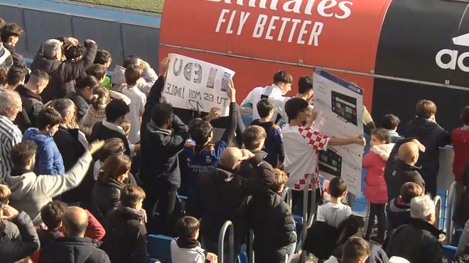Varios pequeños hinchas enseñan sus pancartas a los jugadores del Real Madrid durante el entrenamiento
