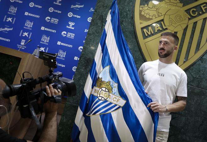 Dioni posa con la bandera del Málaga en su presentación. (Foto: MCF)