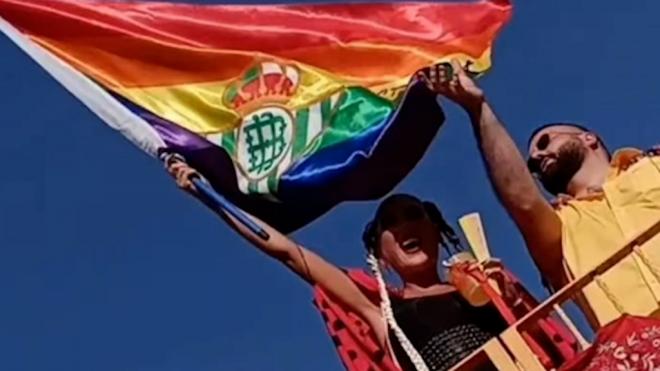 Laura Gallego, con una bandera multicolor con el escudo del Real Betis.
