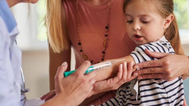 Pediatra poniendo una inyección a una niña