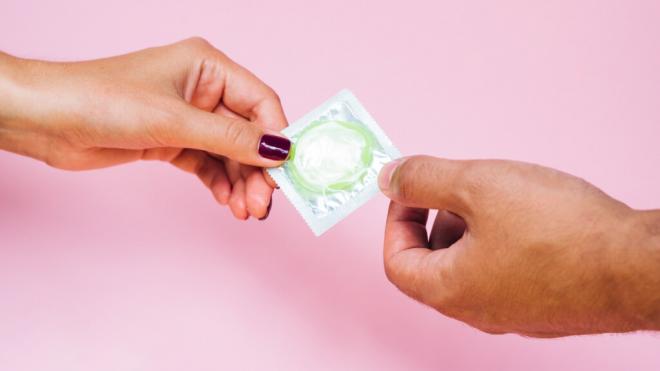 Imagen de recurso de dos manos sosteniendo un preservativo
