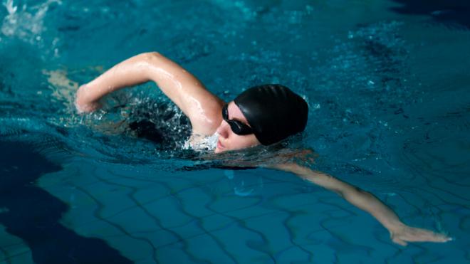 Mujer nadando en una piscina cubierta (Freepik)