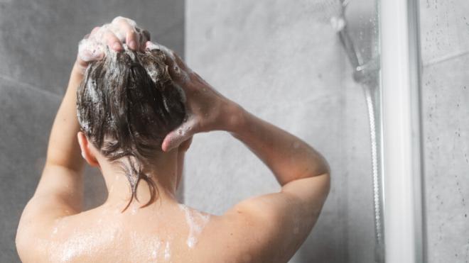 Mujer lavándose el pelo con champú en la ducha (Freepik)