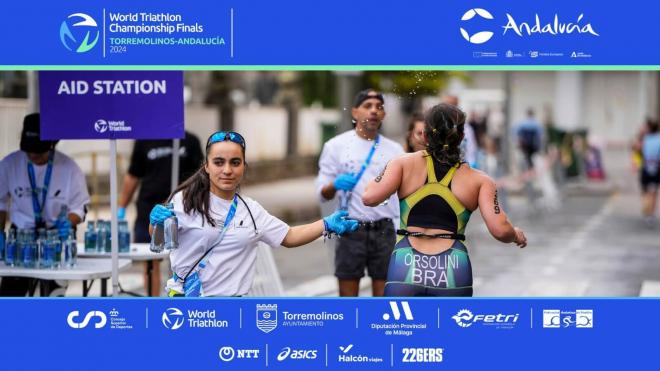 Los voluntarios ofrecen agua a los participantes de triatlón.