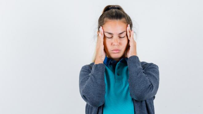 Mujer con migraña con las manos en la sien (Fuente: Freepik)