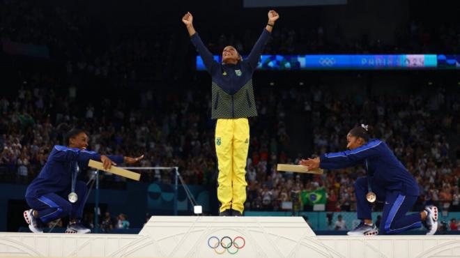 Simone Biles y Jordan Chiles, hacen una reverencia cuando Rebeca Andrade sube al podio (RR.SS).