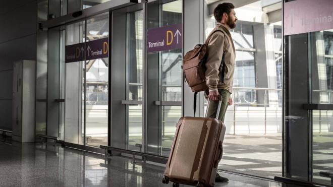 Hombre con una maleta y una mochila en la terminal D de un aeropuerto (Fuente: Freepik)