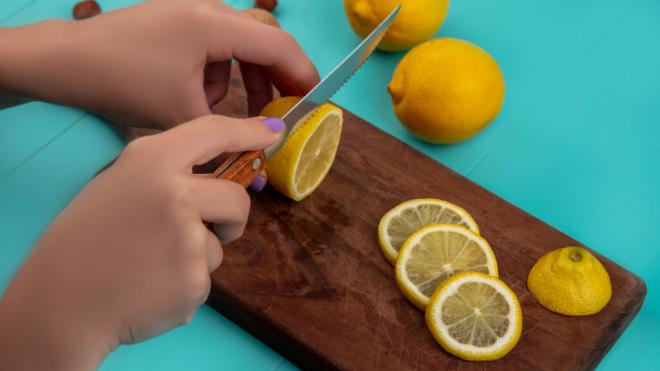 Mujer cortando en rodajas un limón (Fuente: Freepik)