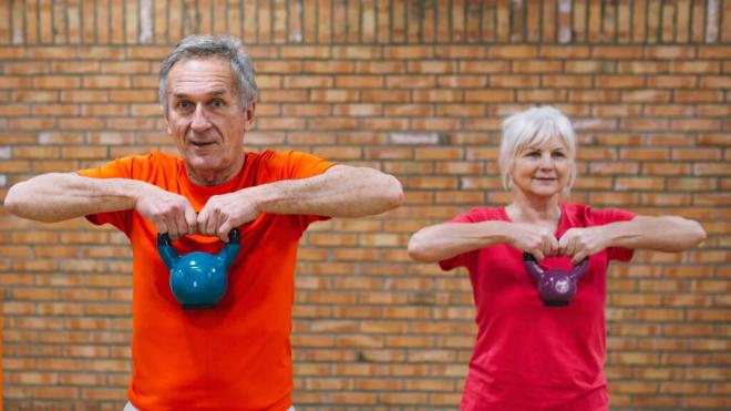 Pareja mayor de hombre y mujer entrenando la fuerza con una kettlebell (Foto: Freepik)