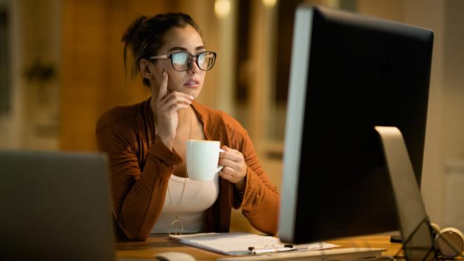 Mujer trabajando frente a una pantalla de noche y tomándose un café (Foto: Freepik)