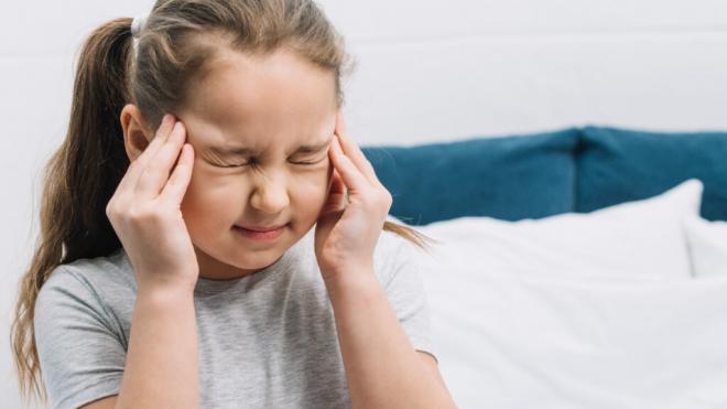 Niña con cara de dolor llevándose las manos a las sienes (Foto: Freepik)