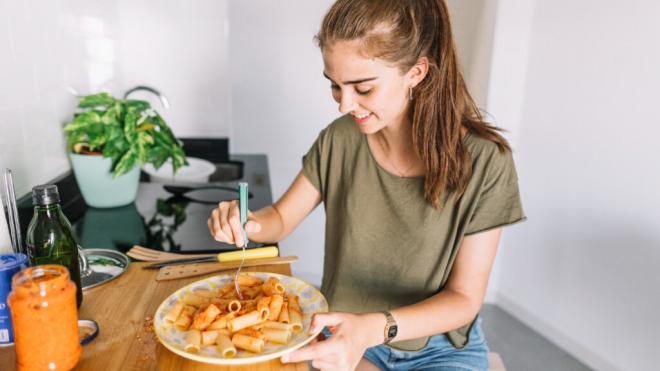 Adolescente comiendo pasta con tomate (Foto: Freepik)