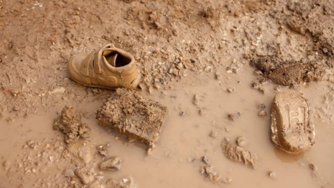 Un par de zapatillas infantiles cubiertas de lodo en una zona anegada de La Torre, Valencia (Foto: EFE)