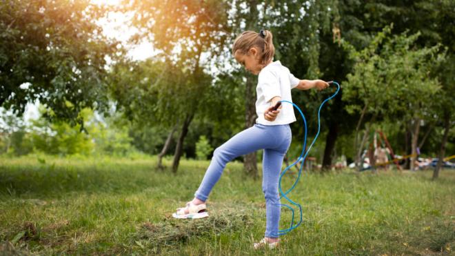 Niña saltando a la comba en una zona verde (Foto: Freepik)