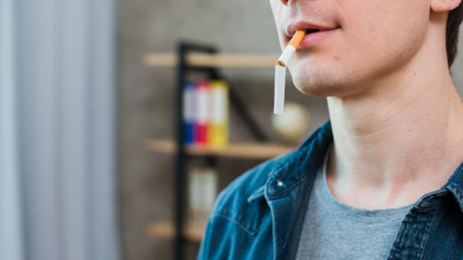 Joven sosteniendo con la boca un cigarro roto (Foto: Freepik)