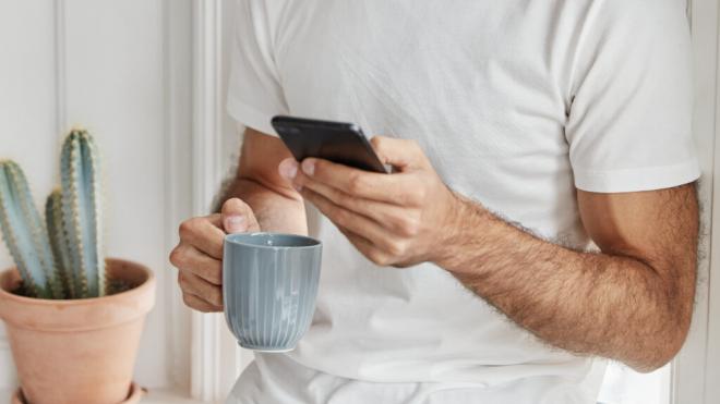 Hombre usando el móvil mientras se toma el café (Foto: Freepik)