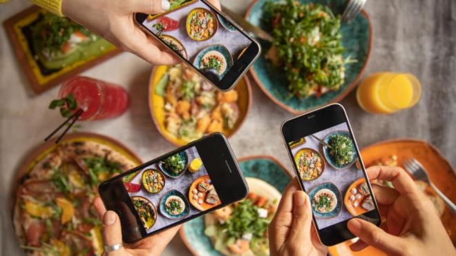 Tres personas fotografiando con el móvil la comida que se van a comer (Foto: Freepik)