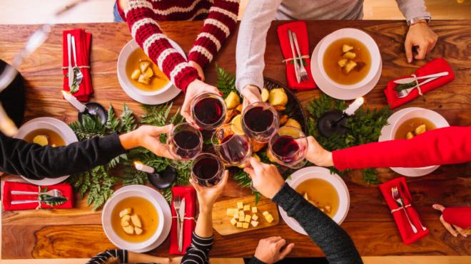 Grupo de personas brindando con vino en una comida navideña (Foto: Freepik)