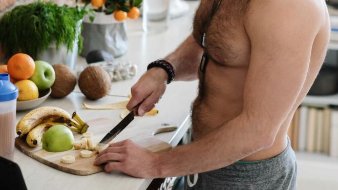 Hombre musculado sin camiseta partiendo fruta (Foto: Freepik)