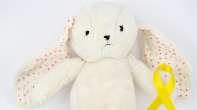 Oso de peluche junto con el lazo amarillo del cáncer infantil (Foto: Freepik)