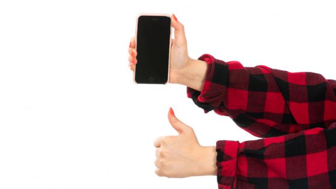 Persona con un smartphone levantando el pulgar (Foto: Freepik)