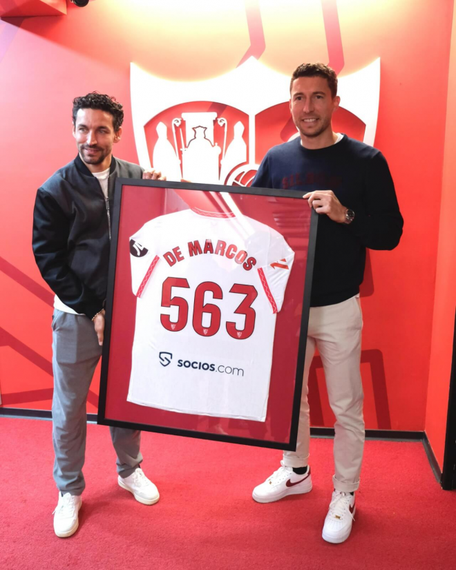 Jesús Navas hace entrega de un regalo sevillista a Óscar de Marcos. (Foto: Sevilla FC)