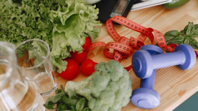 Varias verduras, cinta métrica, mancuernas y báscula de comida (Foto: Freepik)