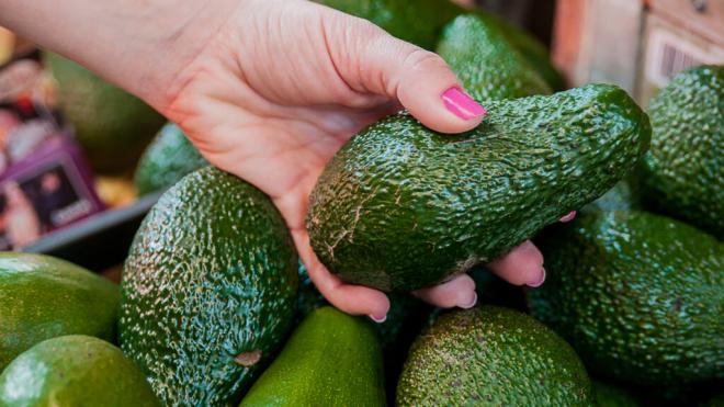 Mujer cogiendo un aguacate de un comercio (Foto: Freepik)