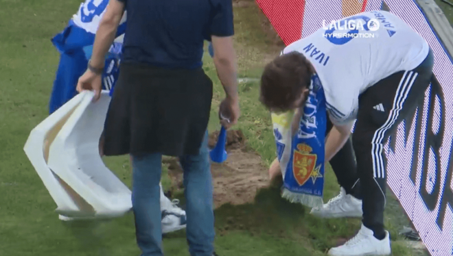 Afionados del Real Zaragoza arrancando trozos de césped de recuerdo.