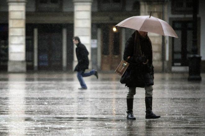 Una mujer se protege de la lluvia con un paraguas (Foto: EFE)