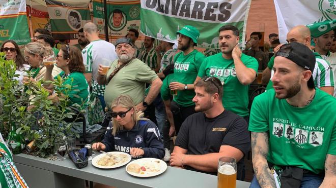 Dos aficionados del Chelsea comen entre aficionados del Betis.