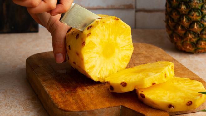 Persona partiendo una piña natural (Foto: Freepik)