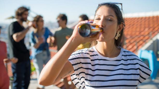 Mujer bebiendo una cerveza en un encuentro con amigos (Foto: Freepik)