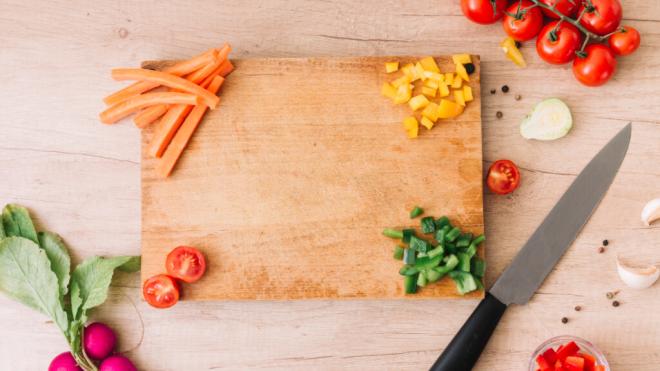 Tabla de cortar de madera con varios alimentos cortados sobre ella (Foto: Freepik)