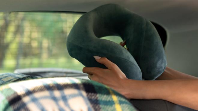 Mujer sosteniendo un cojín del cuello para los viajes (Foto: Freepik)