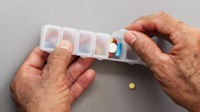Hombre colocando medicación en un pastillero (Foto: Freepik)