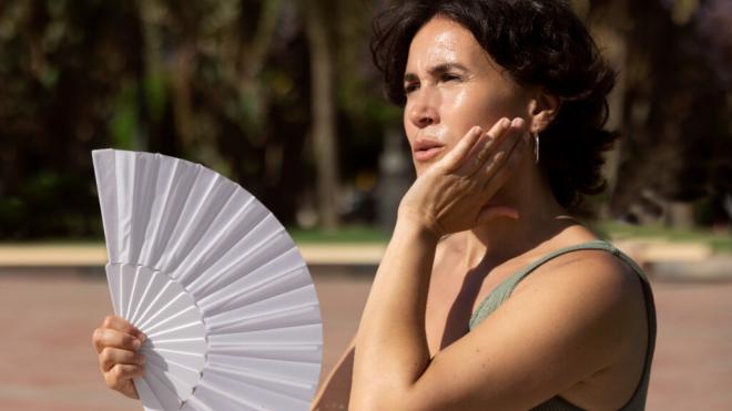 Mujer sudando mientras se abanica (Foto: Freepik)