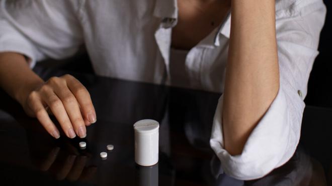 Mujer con unas pastillas sobre la mesa (Foto: Freepik)