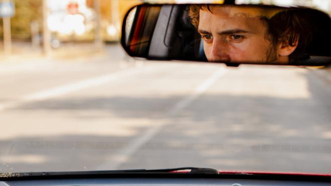 Hombre reflejado en el retrovisor de un coche (Foto: Freepik)