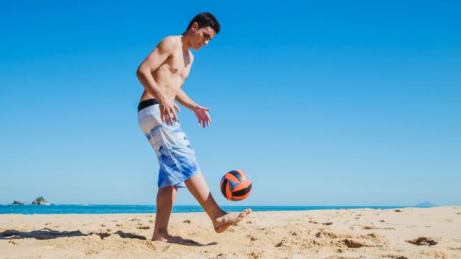 Chico jugando en la playa con un balón (Foto: Freepik)