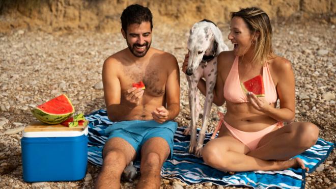 Pareja comiendo sandía en la playa (Foto: Freepik)