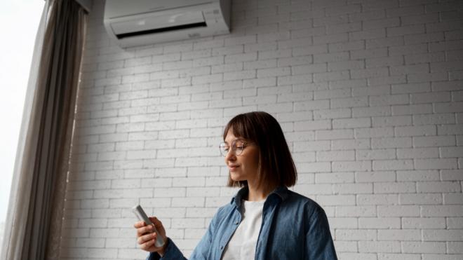 Mujer encendiendo el aire acondicionado (Foto: Freepik)