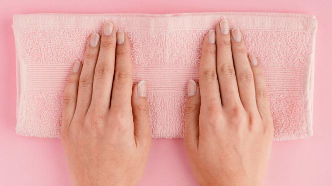 Manos con uñas sin esmalte sobre una toalla (Foto: Freepik)