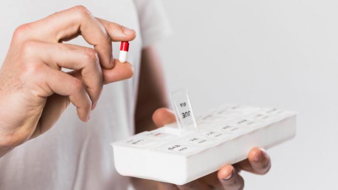 Hombre organizando las pastillas en un pastillero (Foto: Freepik)