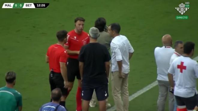 El árbitro intenta tranquilizar a los banquillos de Betis y Málaga.